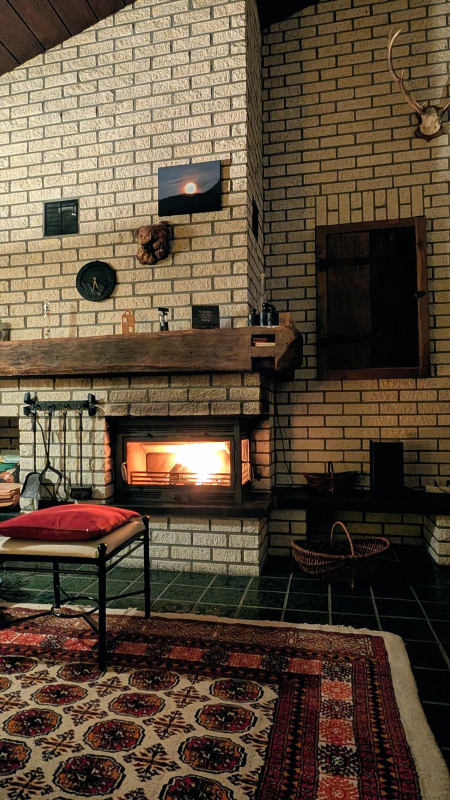 Salon rustique en briques claires avec insert de cheminée allumé